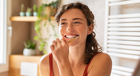 Patient smiling while brushing her teeth