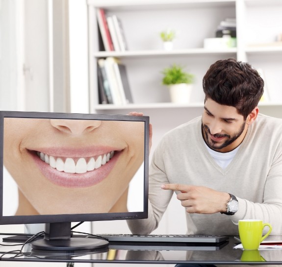 Man pointing to computer monitor showing smile with straight white teeth