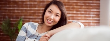 Young woman relaxing on couch after receiving dental services in Raleigh