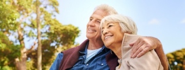Smiling senior man and woman sitting on park bench