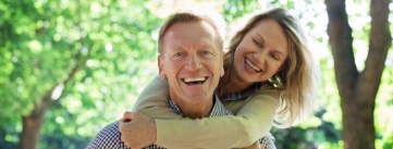 Smiling woman hugging man from behind outdoors