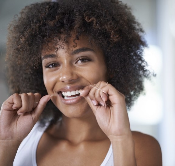 Woman smiling while flossing her teeth