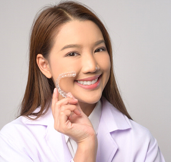 Woman in white shirt holding clear aligner