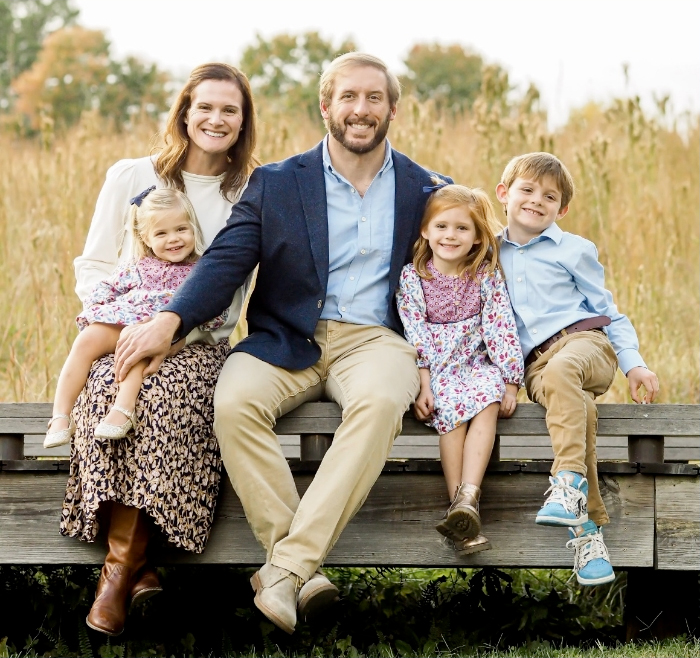 Doctor Hunt smiling on bench with her husband and three children