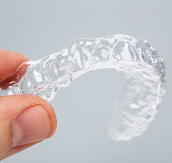 Hand holding an Invisalign clear aligner