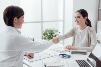 Woman shaking hands with her dentist from across a desk