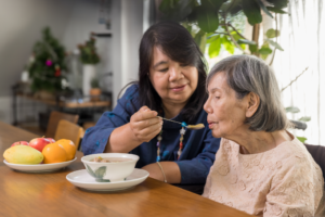a woman helping feed her senior parent oatmeal