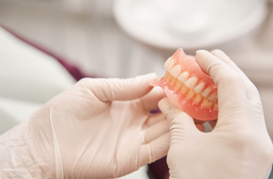 Gloved hands holding dentures